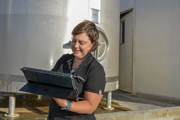 Heidi from Summit Business Solutions working on a laptop on site at a dairy farm.